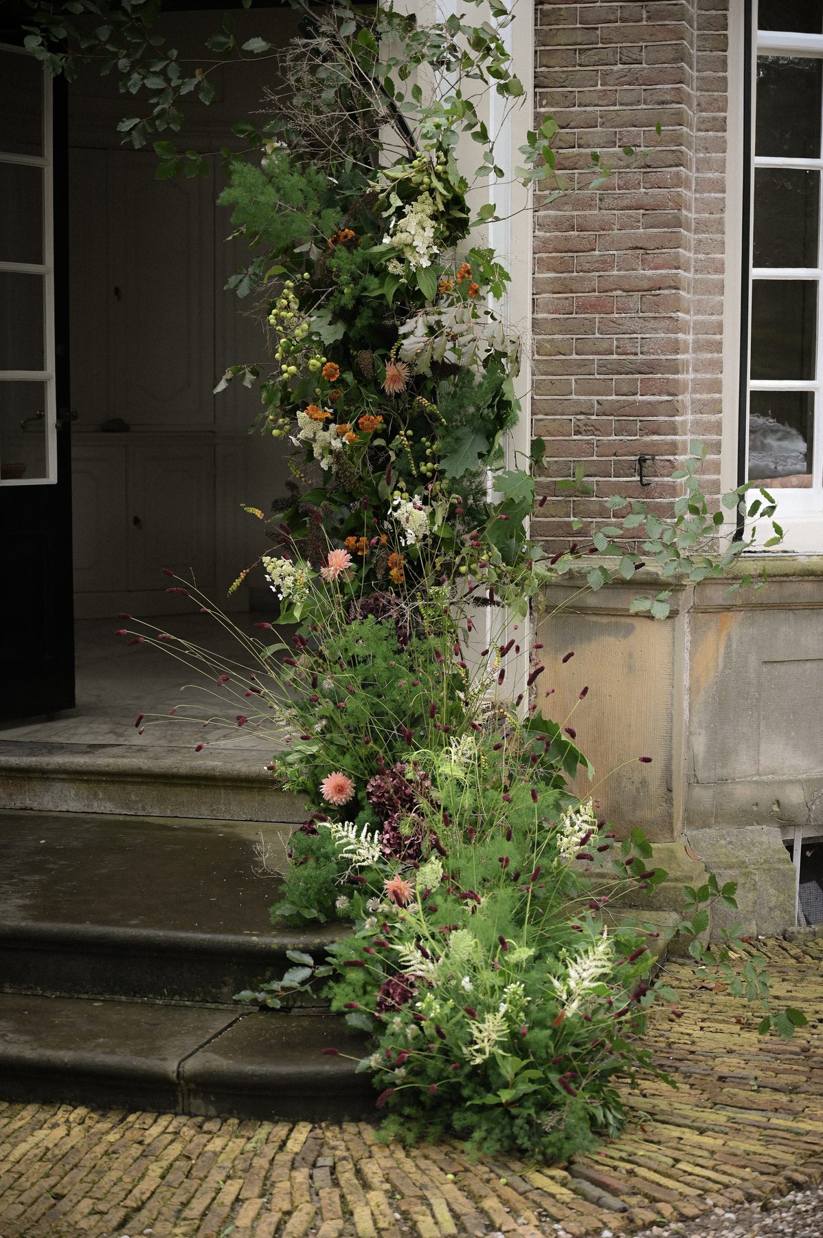 Bloeminstallatie langs een voordeur met lantaarn